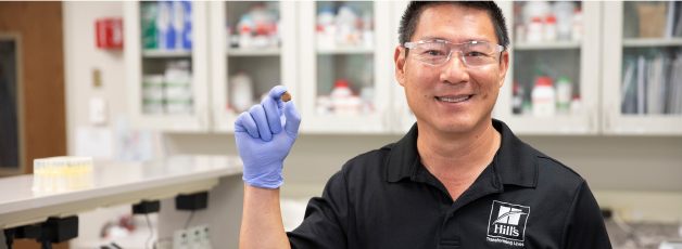 Výzkumník společnosti Hill's držící v ruce granule krmiva Hill's